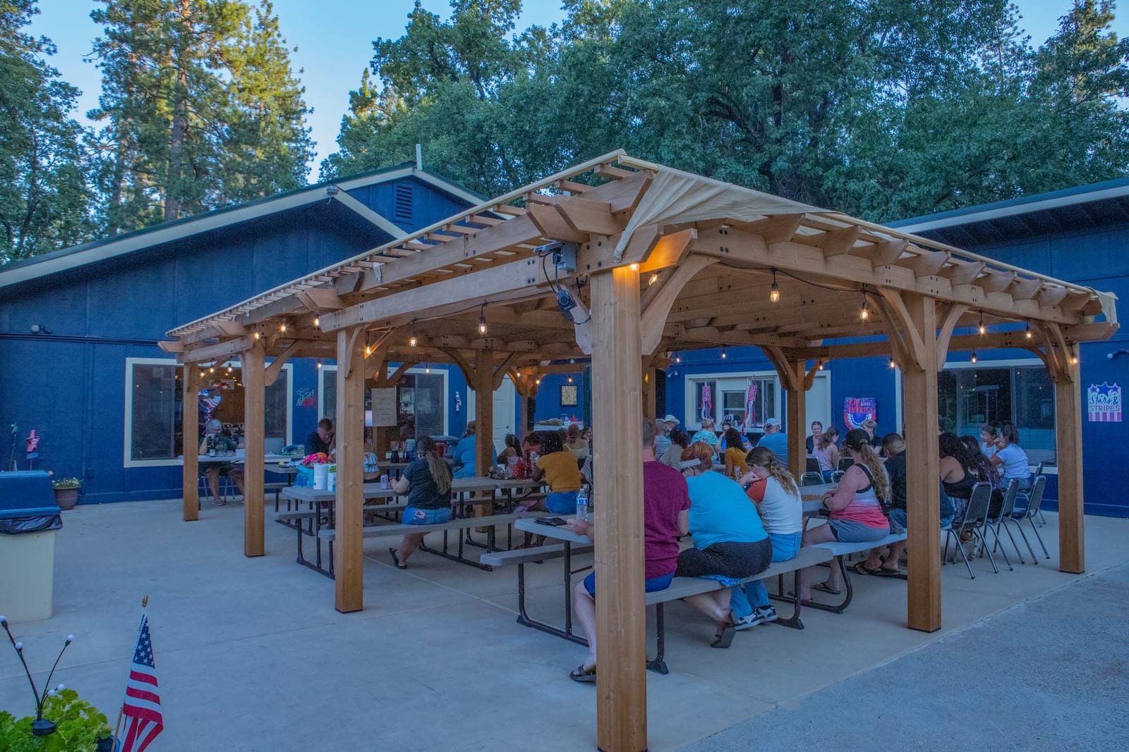Guests gathered under the pergola beside the navy clubhouse at Outdoorsy Yosemite
