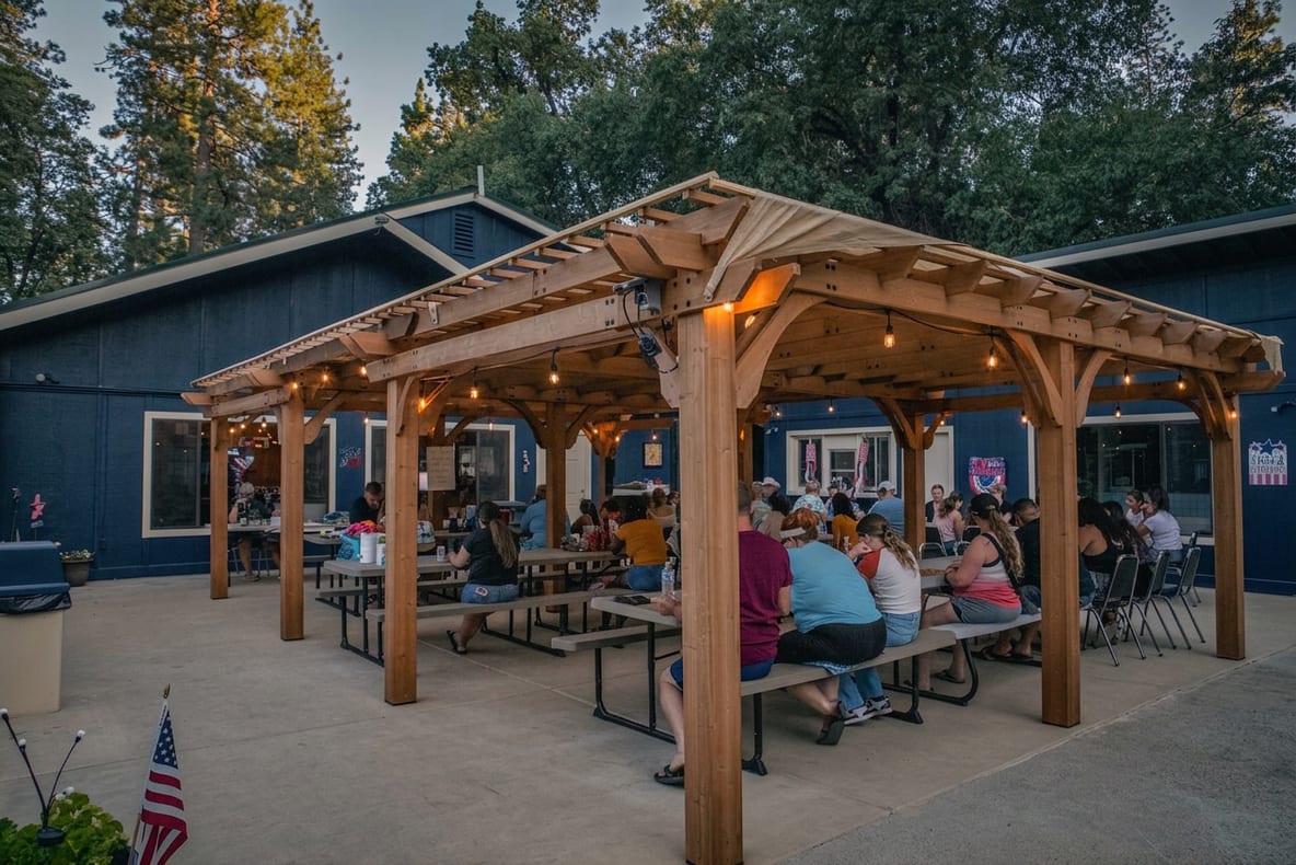 Guests gathered under the pergola beside the navy clubhouse at Outdoorsy Yosemite