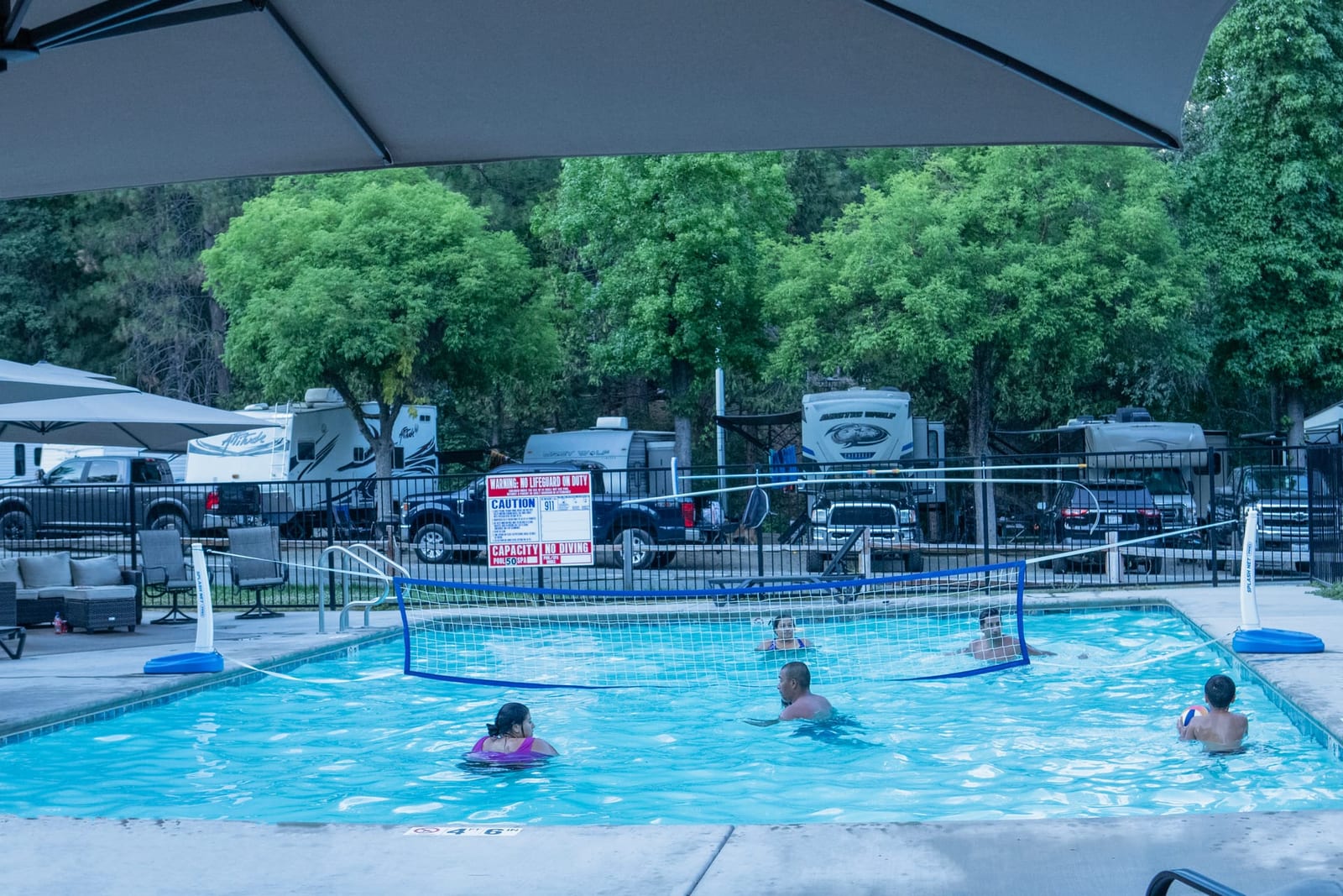 Guests in the seasonal pool beside the navy clubhouse at Outdoorsy Yosemite
