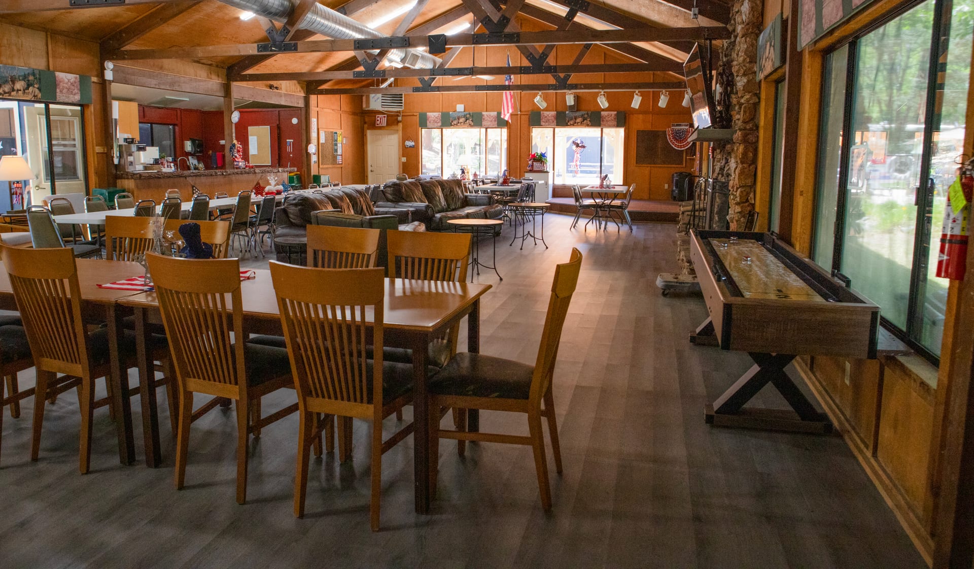 Adult Clubhouse interior with dining tables, sectional lounge, and shuffleboard at Outdoorsy Yosemite