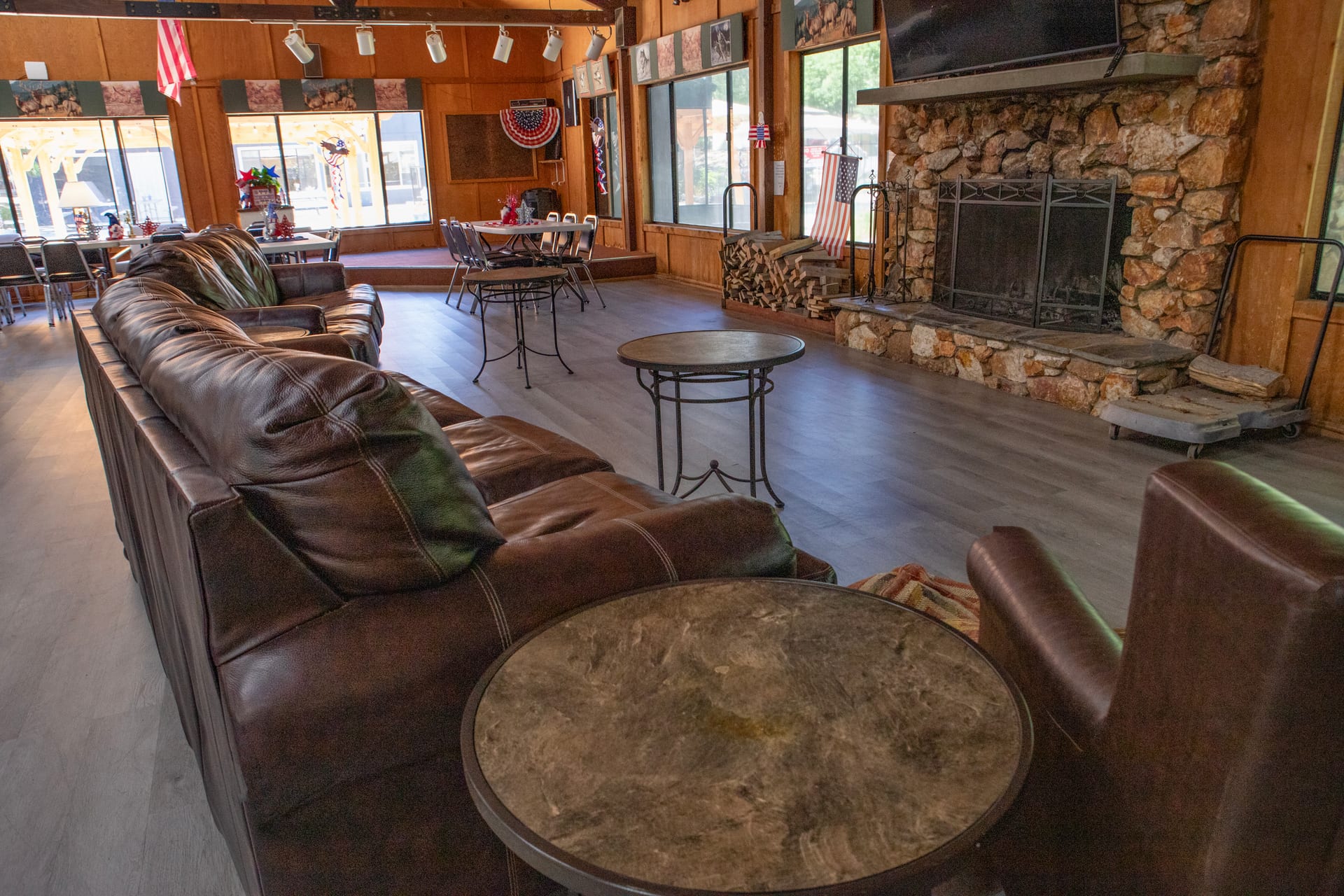 Adult Clubhouse interior with leather sectional and stone fireplace at Outdoorsy Yosemite